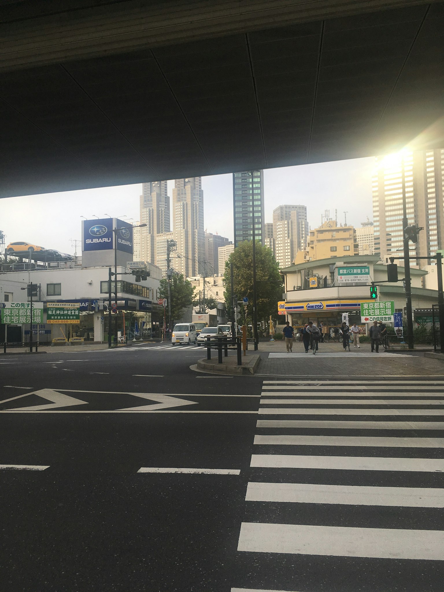 ทิวทัศน์ของสี่แยกในเมือง มีตึกระฟ้าอยู่เบื้องหลัง คนเดินข้ามถนน