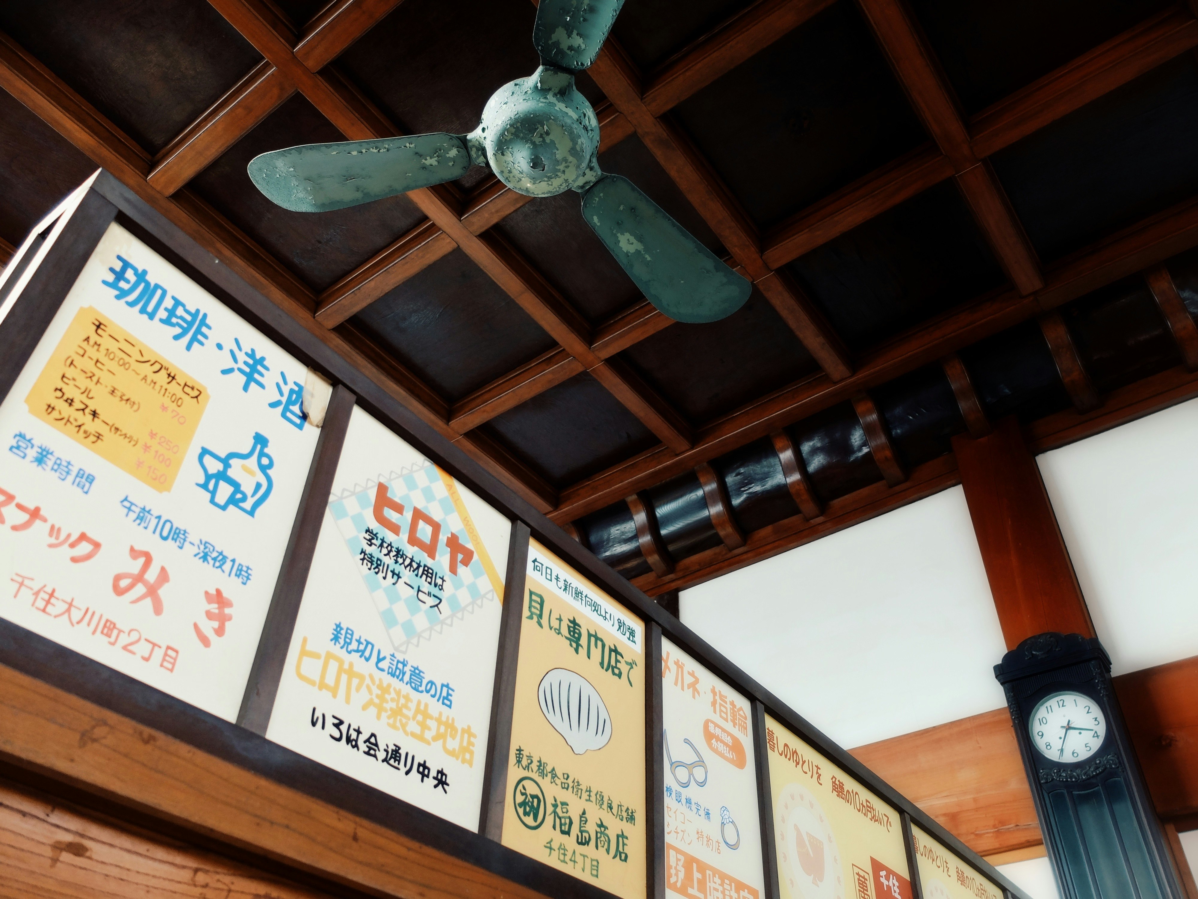 銭湯の脱衣所に掲示されたレトロな案内ポスターと時計のある天井