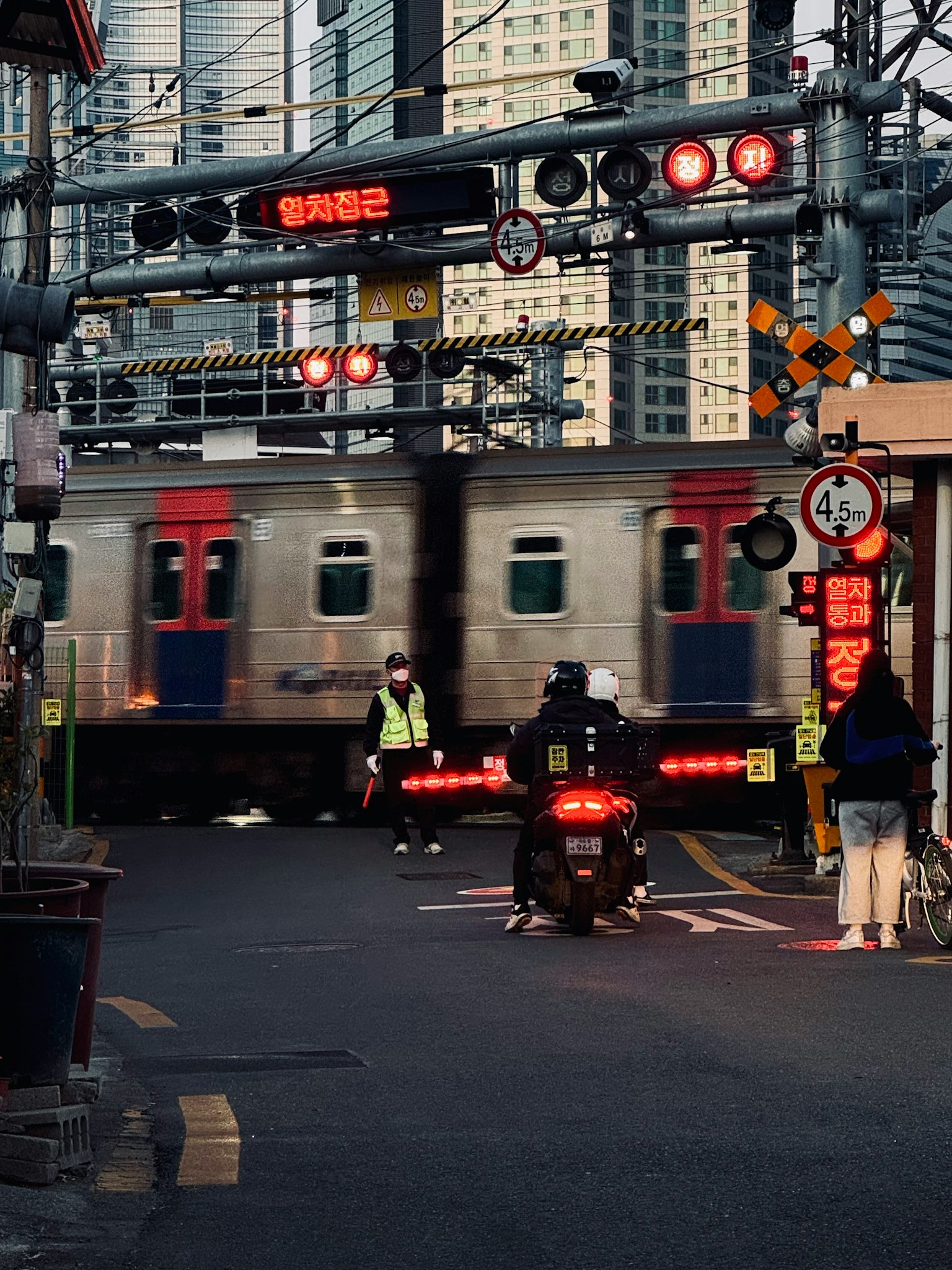 都市の鉄道交差点で通過する列車と信号機が見える
