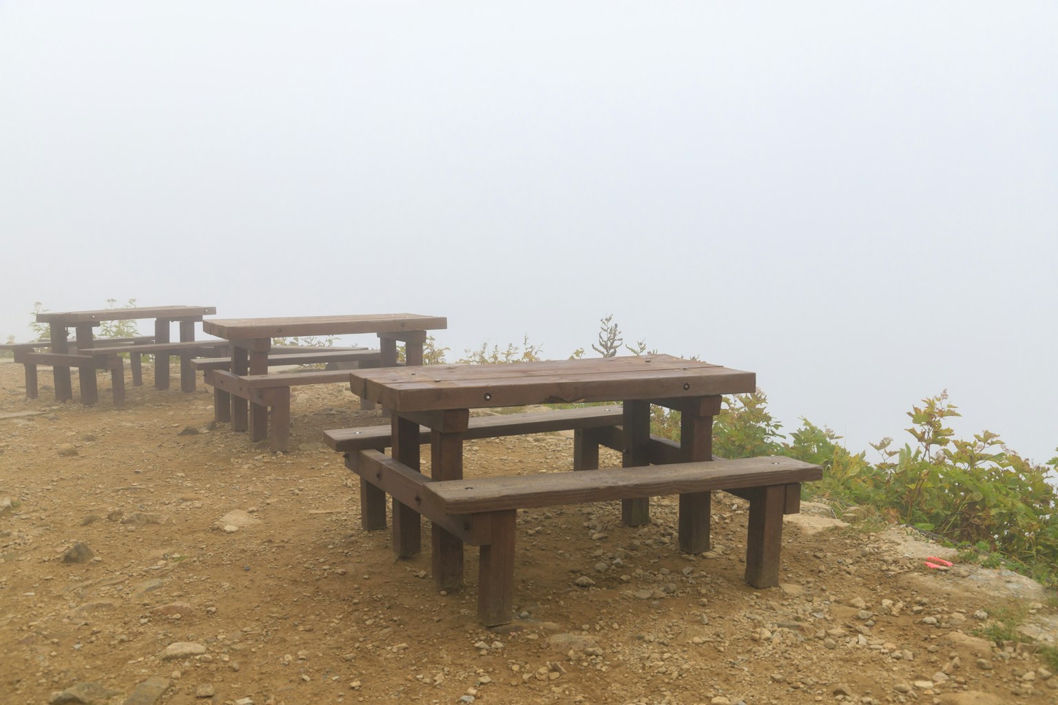 Holztische und -bänke in nebliger Umgebung