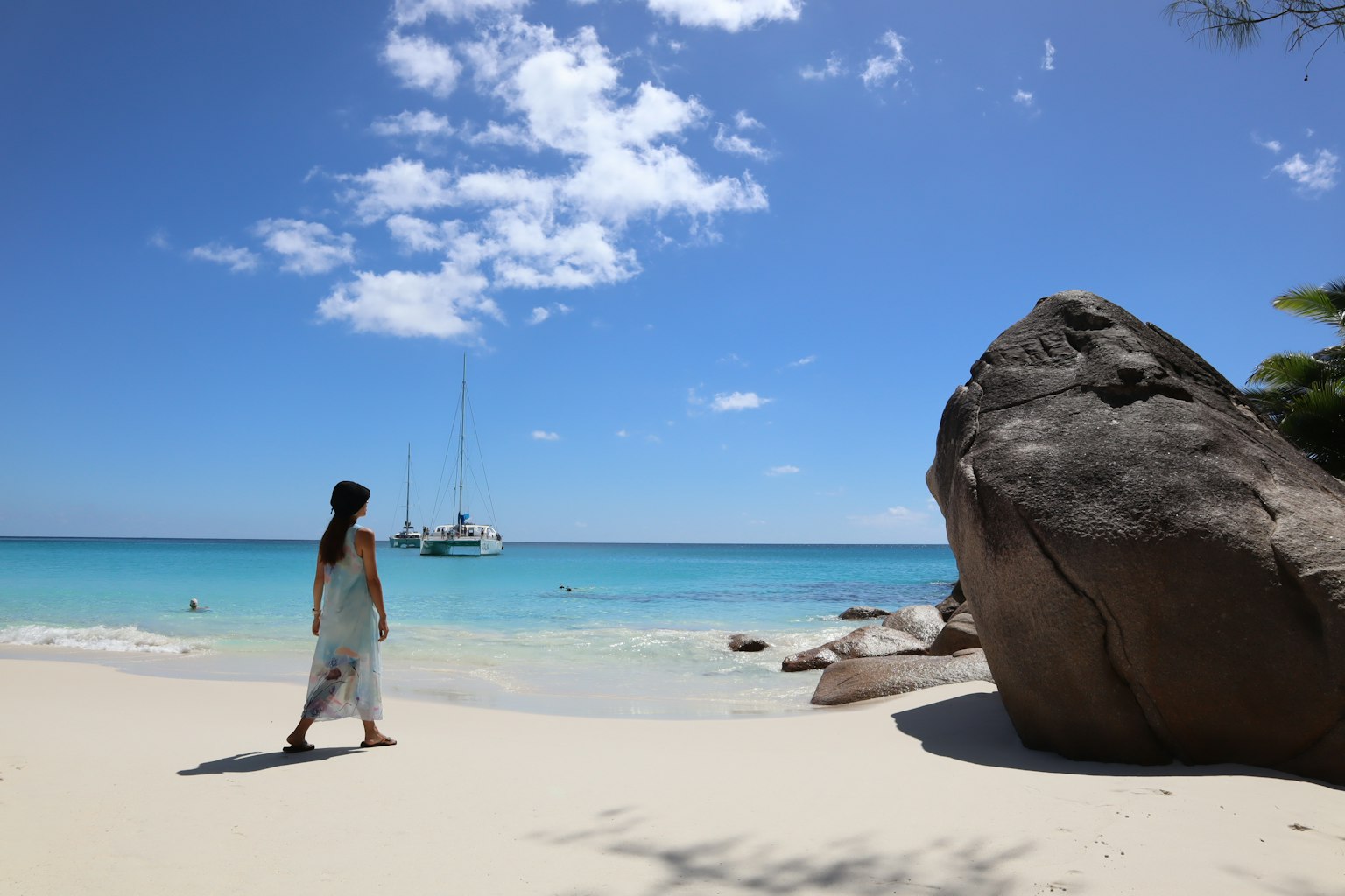 Une femme marchant sur une plage avec de l'eau bleue et du sable blanc