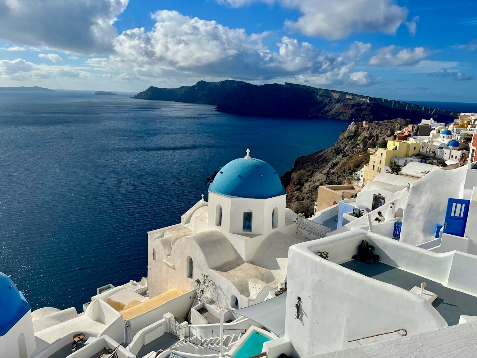 Vista costera con cúpula azul y edificios blancos de Santorini
