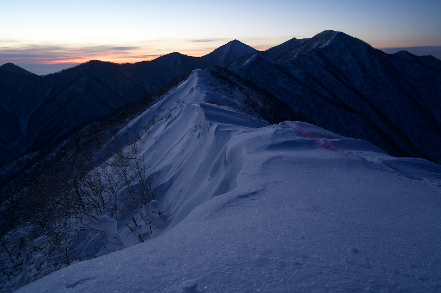 Crête montagneuse enneigée avec ciel au coucher de soleil
