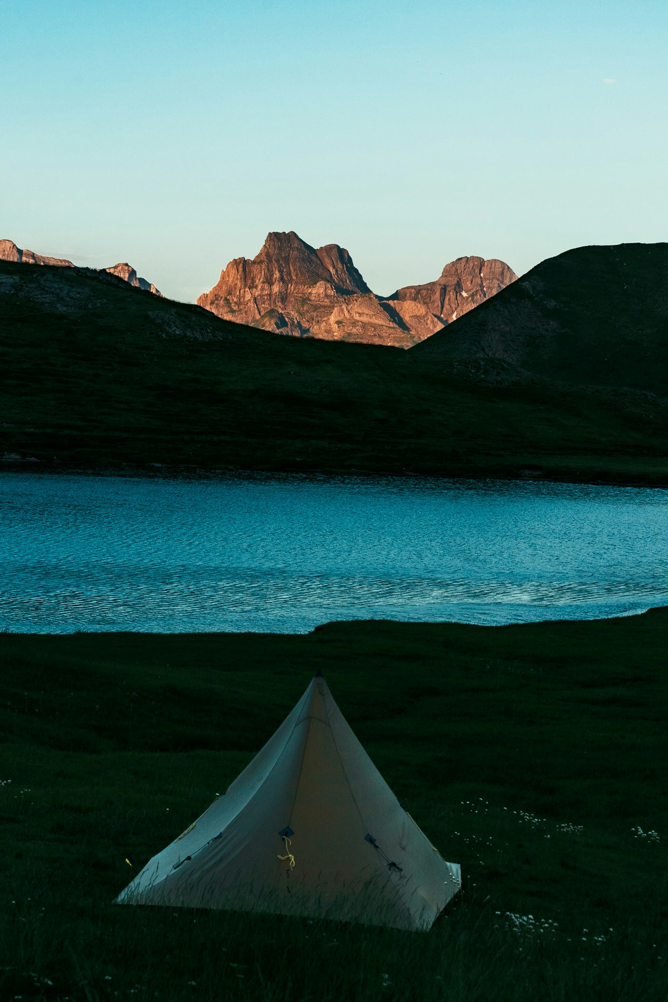 湖边帐篷与夕阳下的群山