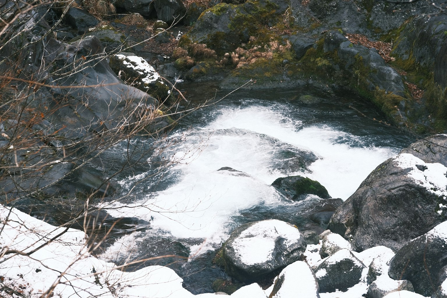 Foto di acqua che scorre su rocce coperte di neve