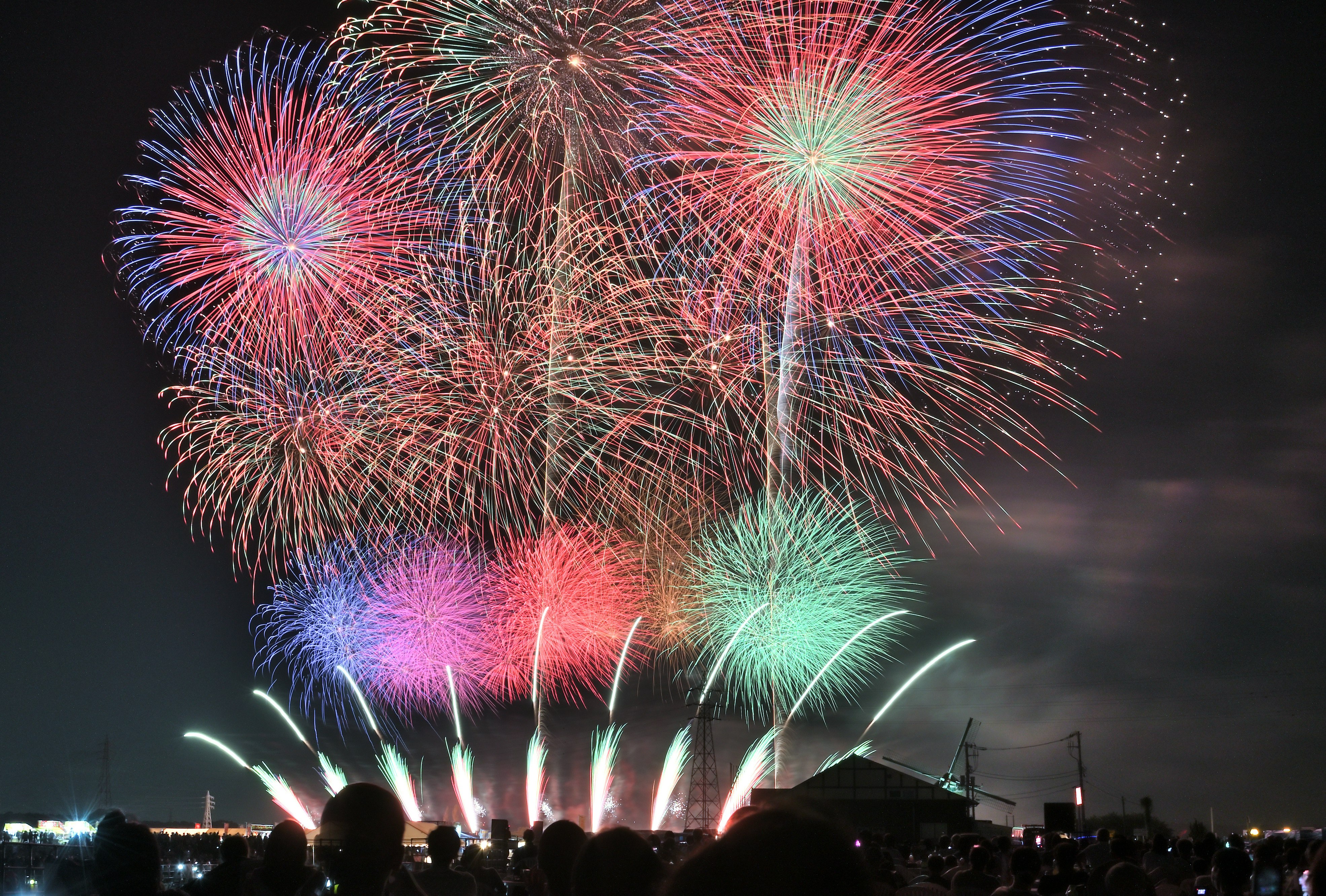 夜空に広がる色とりどりの花火と観客のシルエット