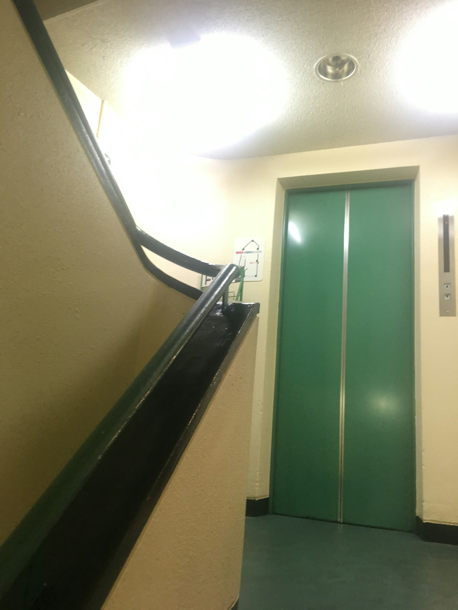 Vista interior con escalera y ascensor verde