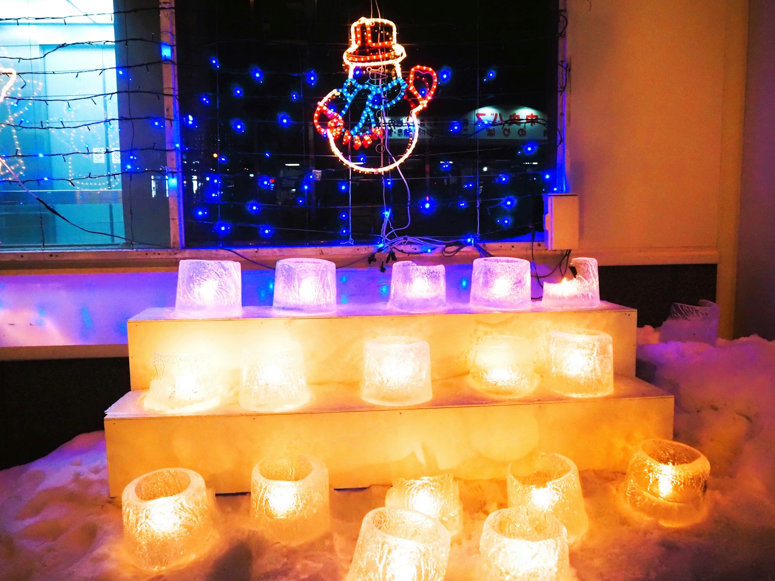 Snowman decoration with illuminated ice candles and festive lights