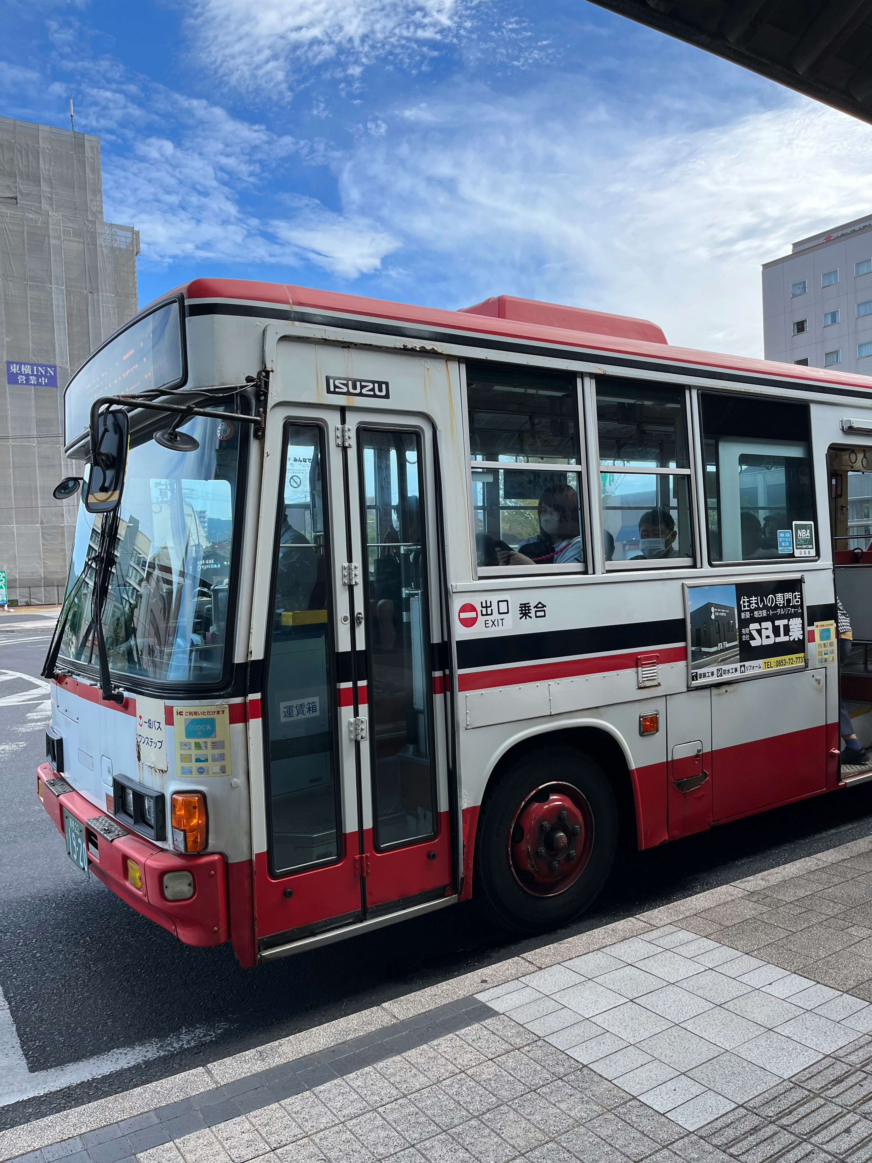 赤い路線バスが停車する街中の交差点