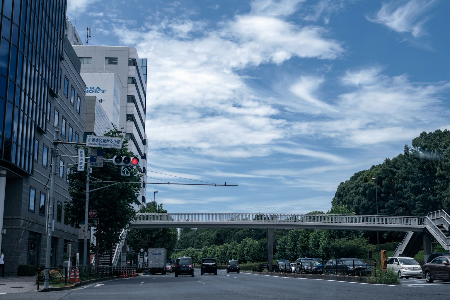 Städtische Landschaft mit blauem Himmel und Wolken mit einer Straße und einer Fußgängerbrücke