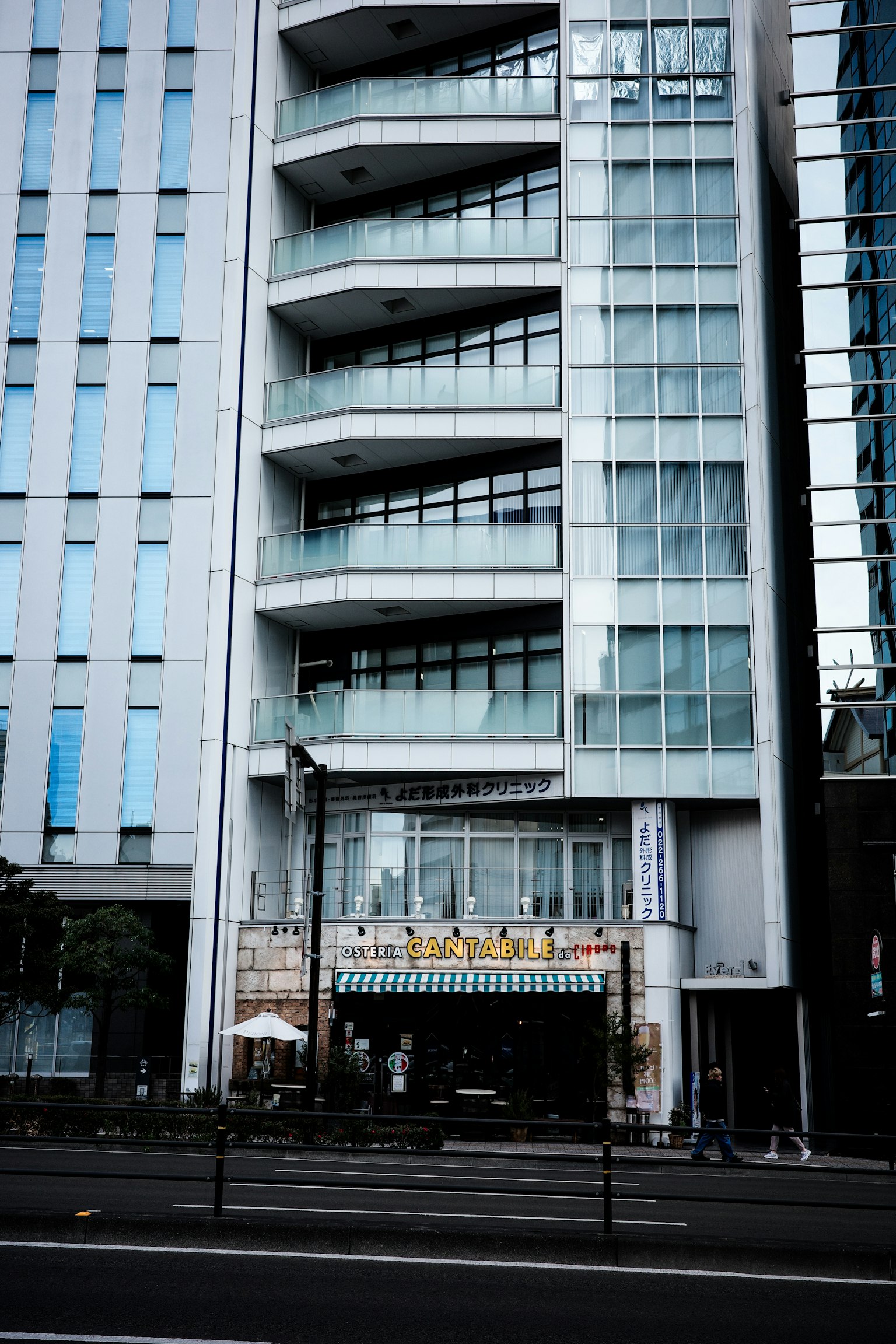 Vista de una calle de un edificio moderno con fachada de vidrio y balcones únicos