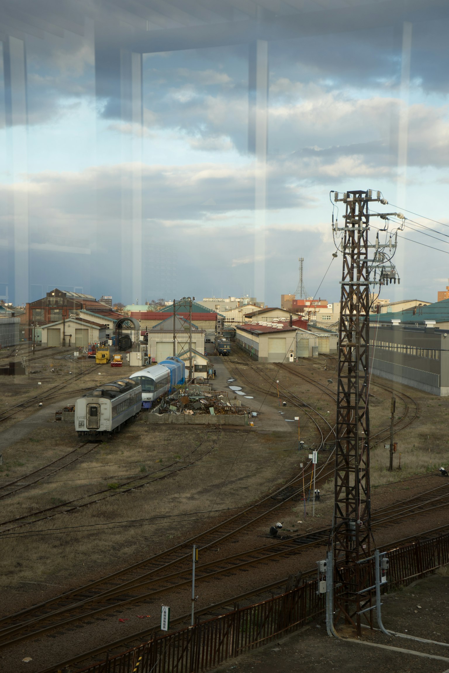 Paisaje industrial con una torre eléctrica y un tren de carga bajo un cielo nublado