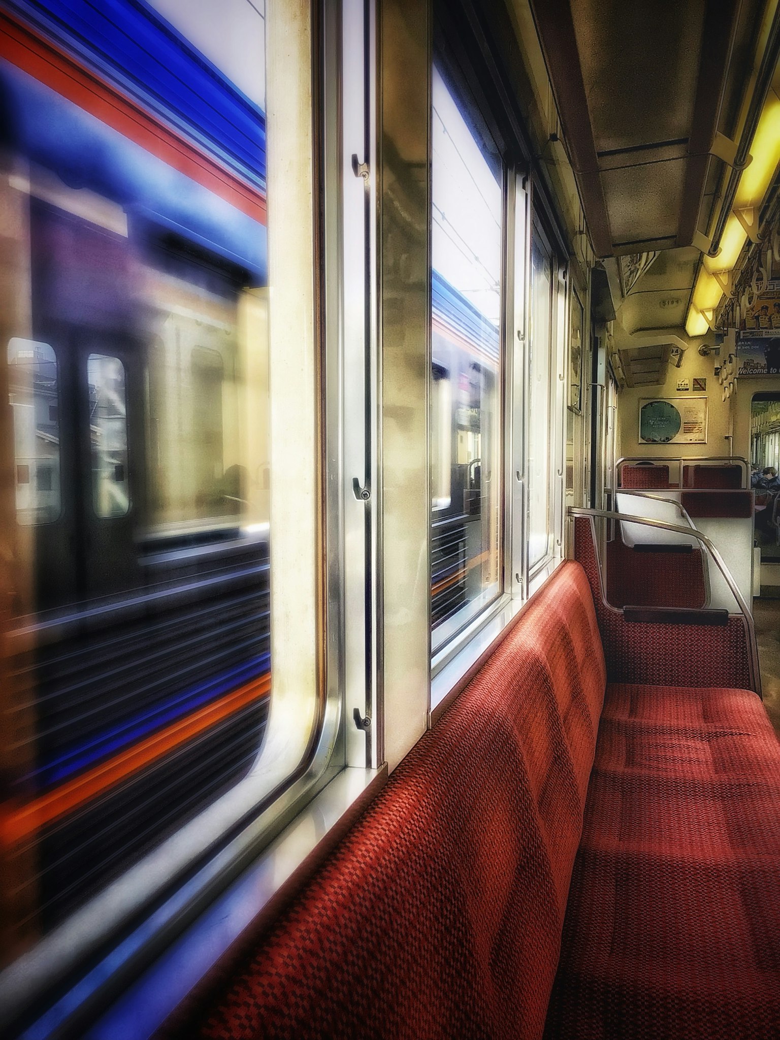 Innenraum eines U-Bahn-Zuges mit roten Sitzen und verschwommenem Blick durch das Fenster