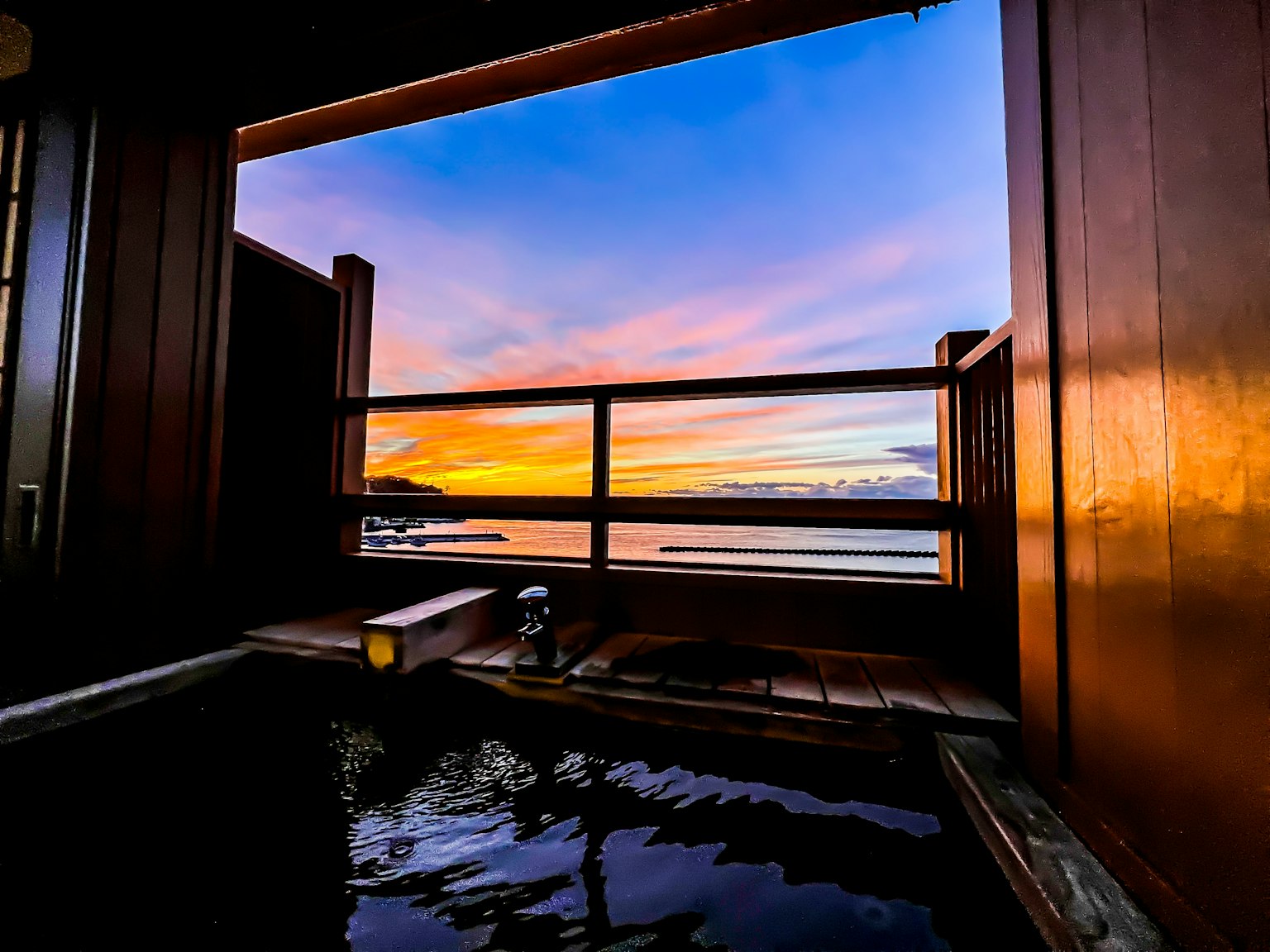 Vista escénica de un manantial exterior al atardecer con reflejos coloridos en el agua