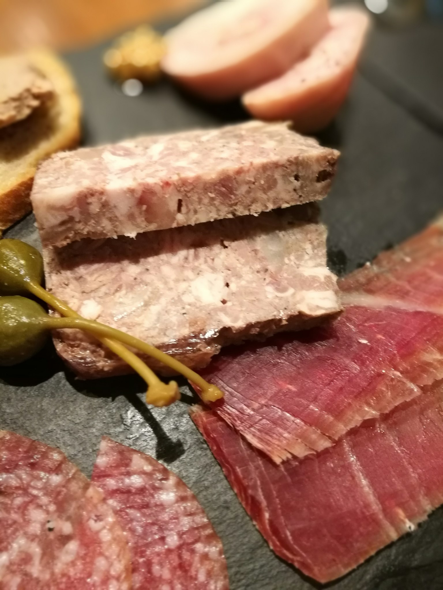 特寫的肉類拼盤，包括肉醬和各種腌製肉類