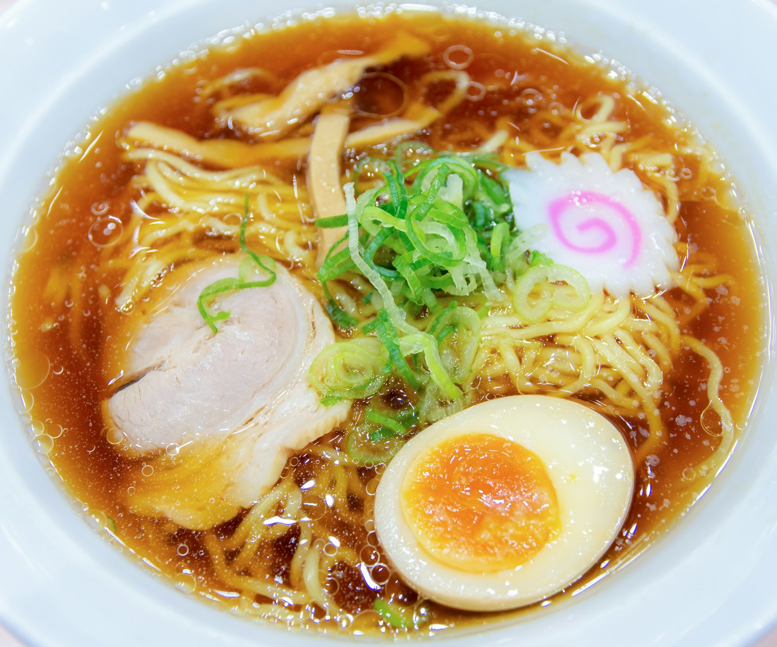 Eine Schüssel Ramen mit Chashu, Frühlingszwiebeln, Naruto und einem weichgekochten Ei