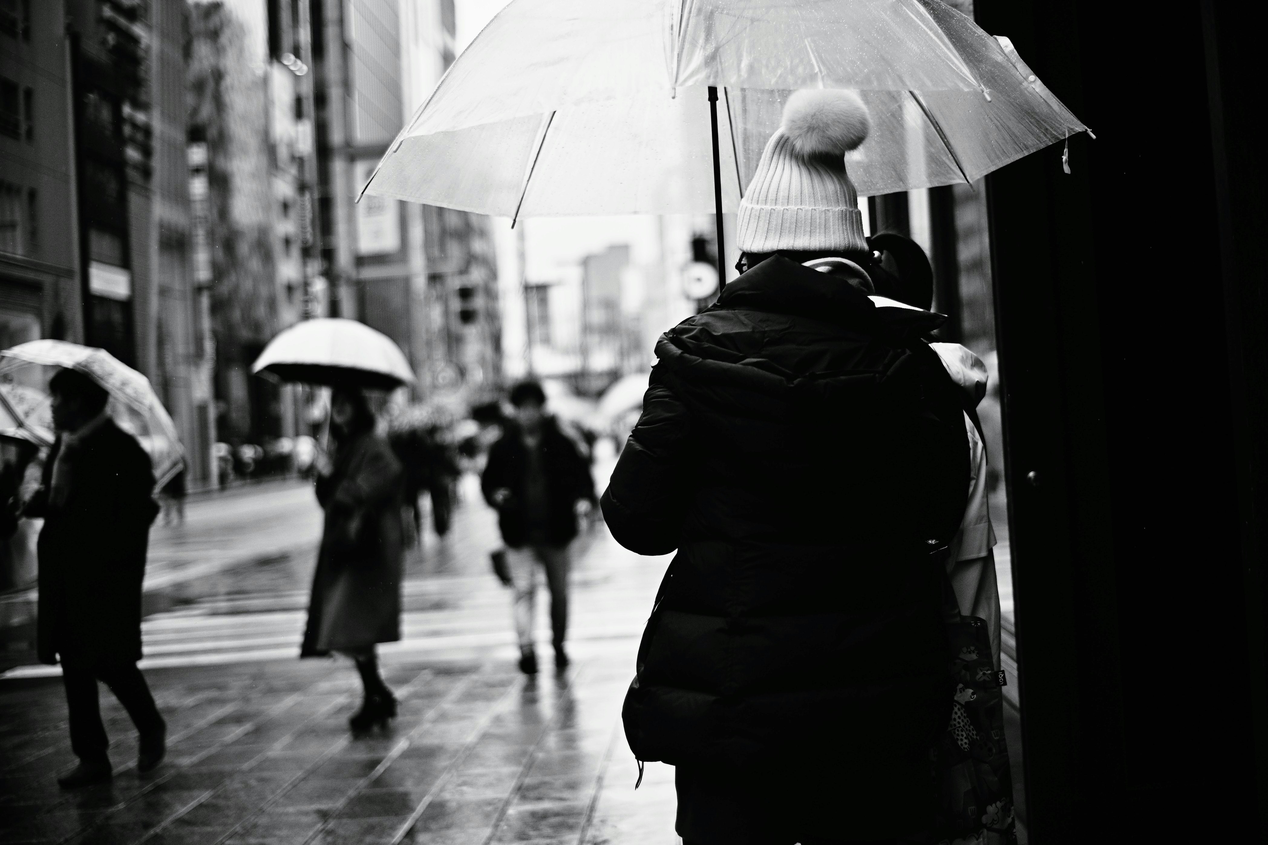 雨の街で傘をさす人々の路地風景