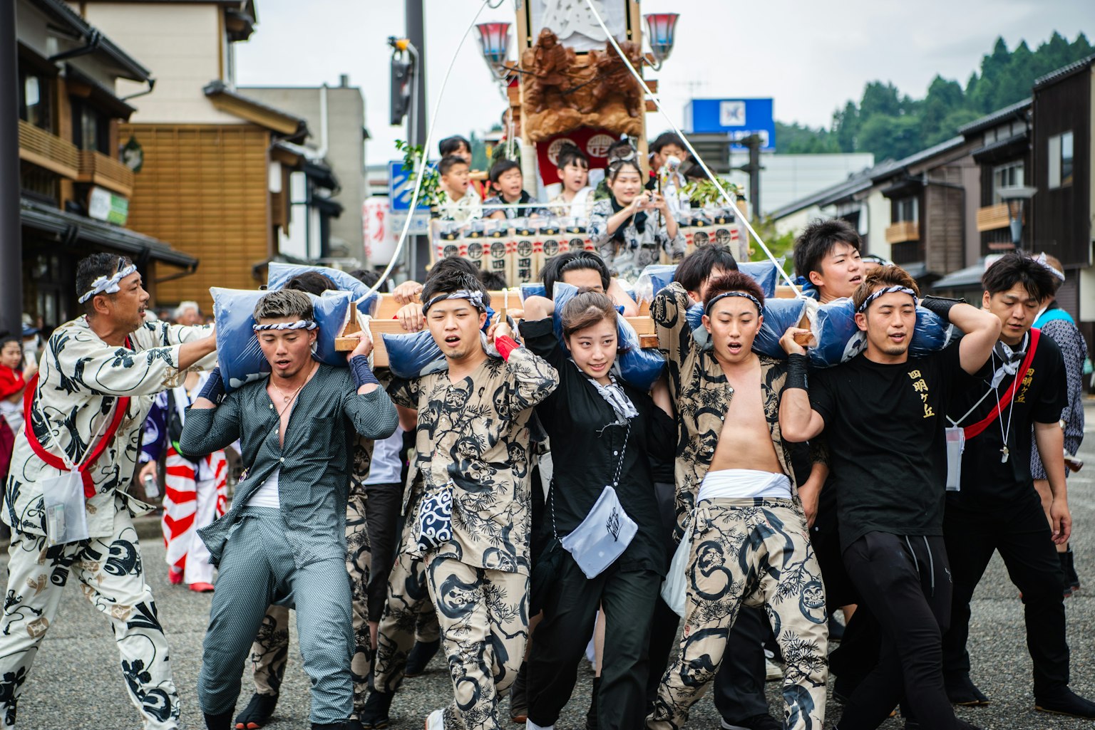 身穿傳統服裝的男性在節日遊行中抬著便攜神社