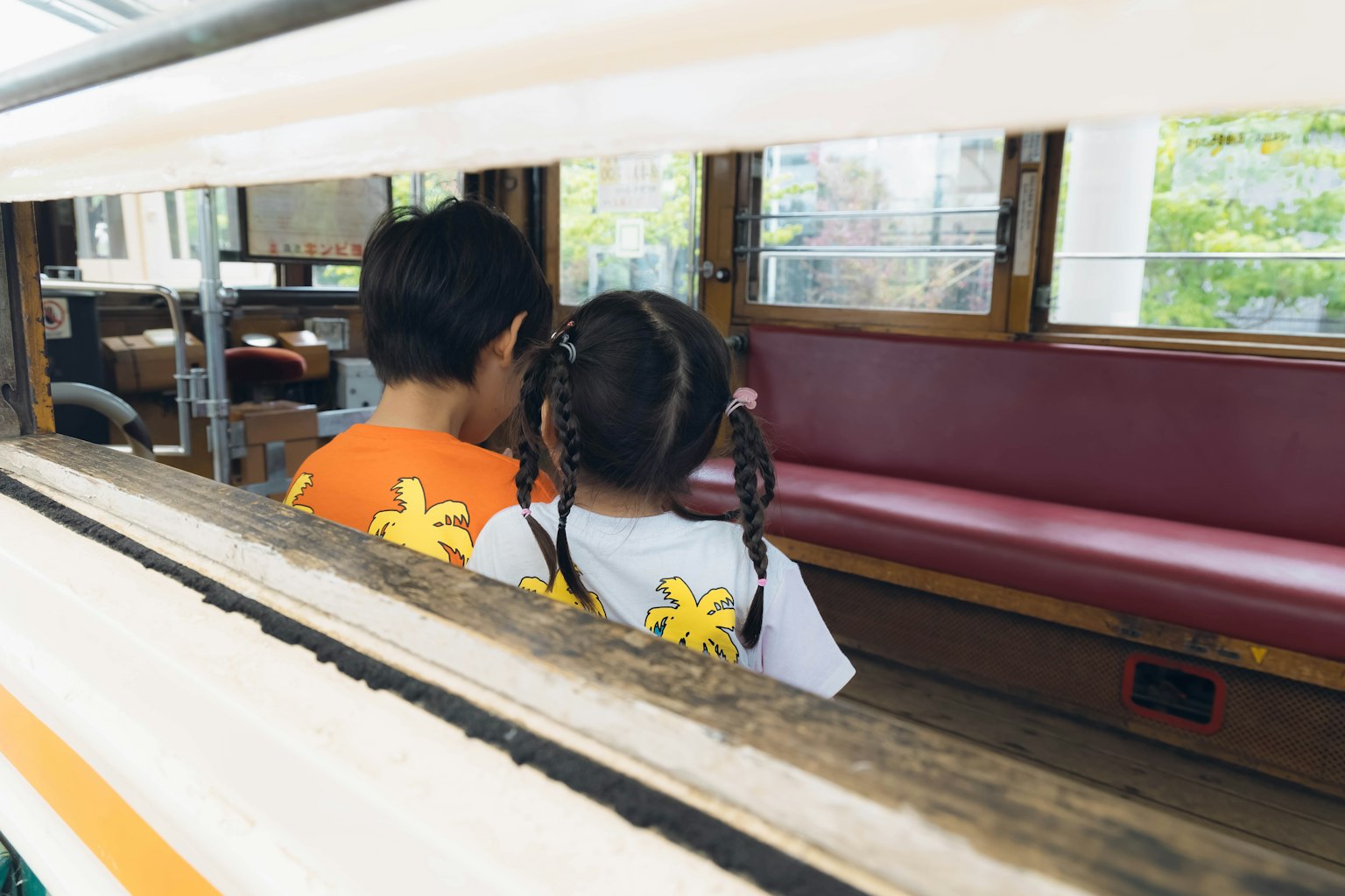 Due bambini seduti vicini con le spalle rivolte verso la fotocamera