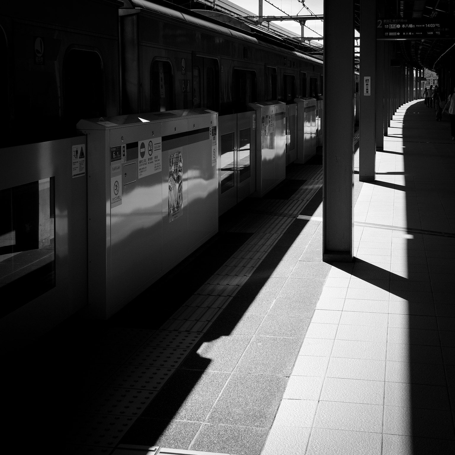 Immagine in bianco e nero di una piattaforma ferroviaria con carrozze e ombre