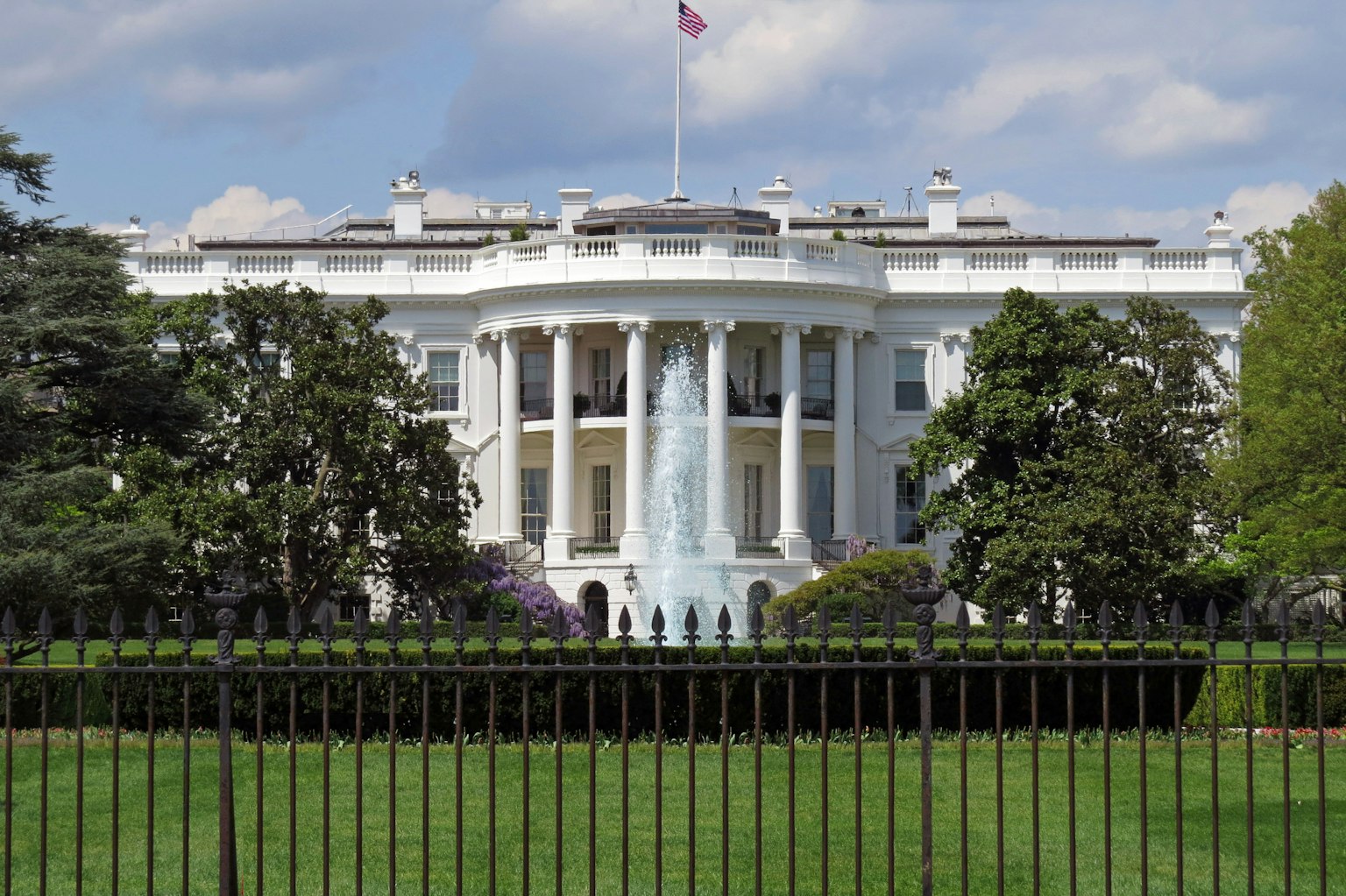 Front view of the White House with green lawn and trees