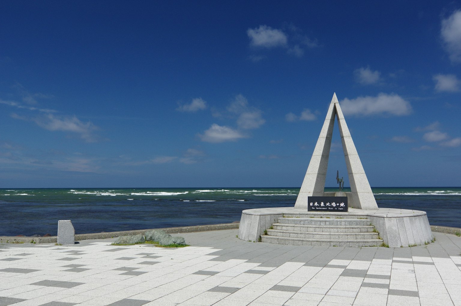 三角形石碑，背景為藍天和海洋