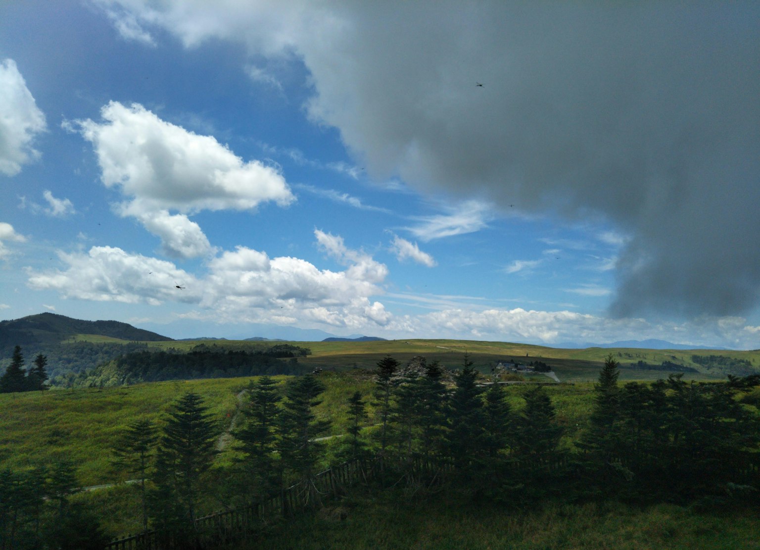 Üppige grüne Hügel mit blauem Himmel und Wolken im Hintergrund
