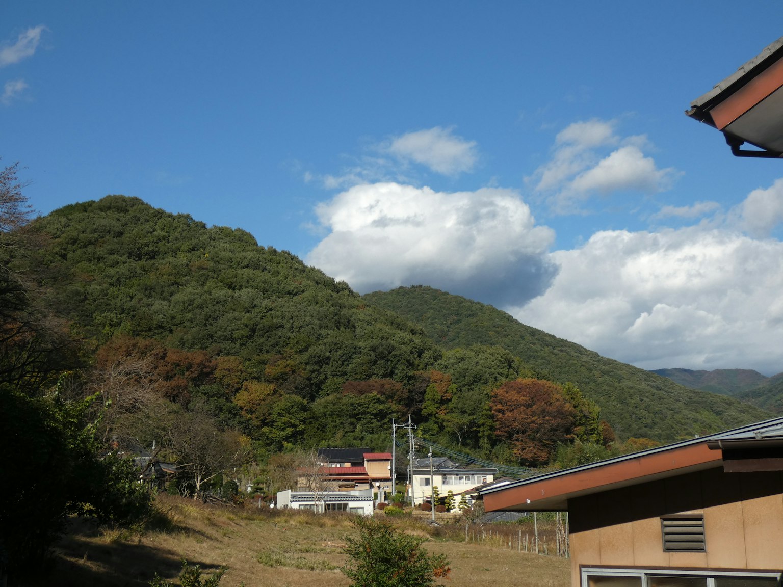 Berglandschaft mit blauem Himmel und weißen Wolken grüne Hügel und ein ruhiges Dorf in Sicht