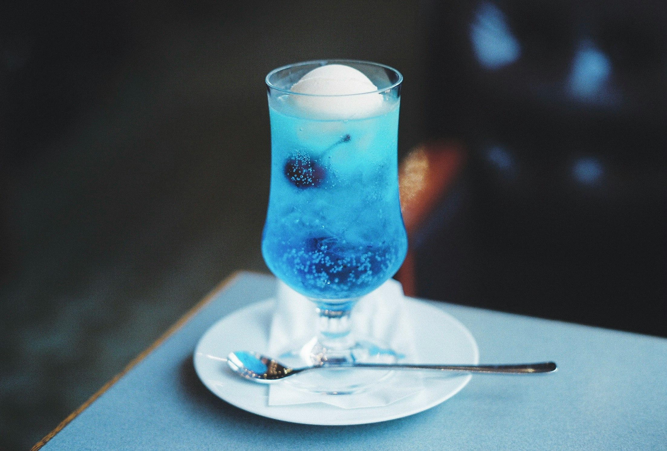 blue cocktail glass with ice on a table
