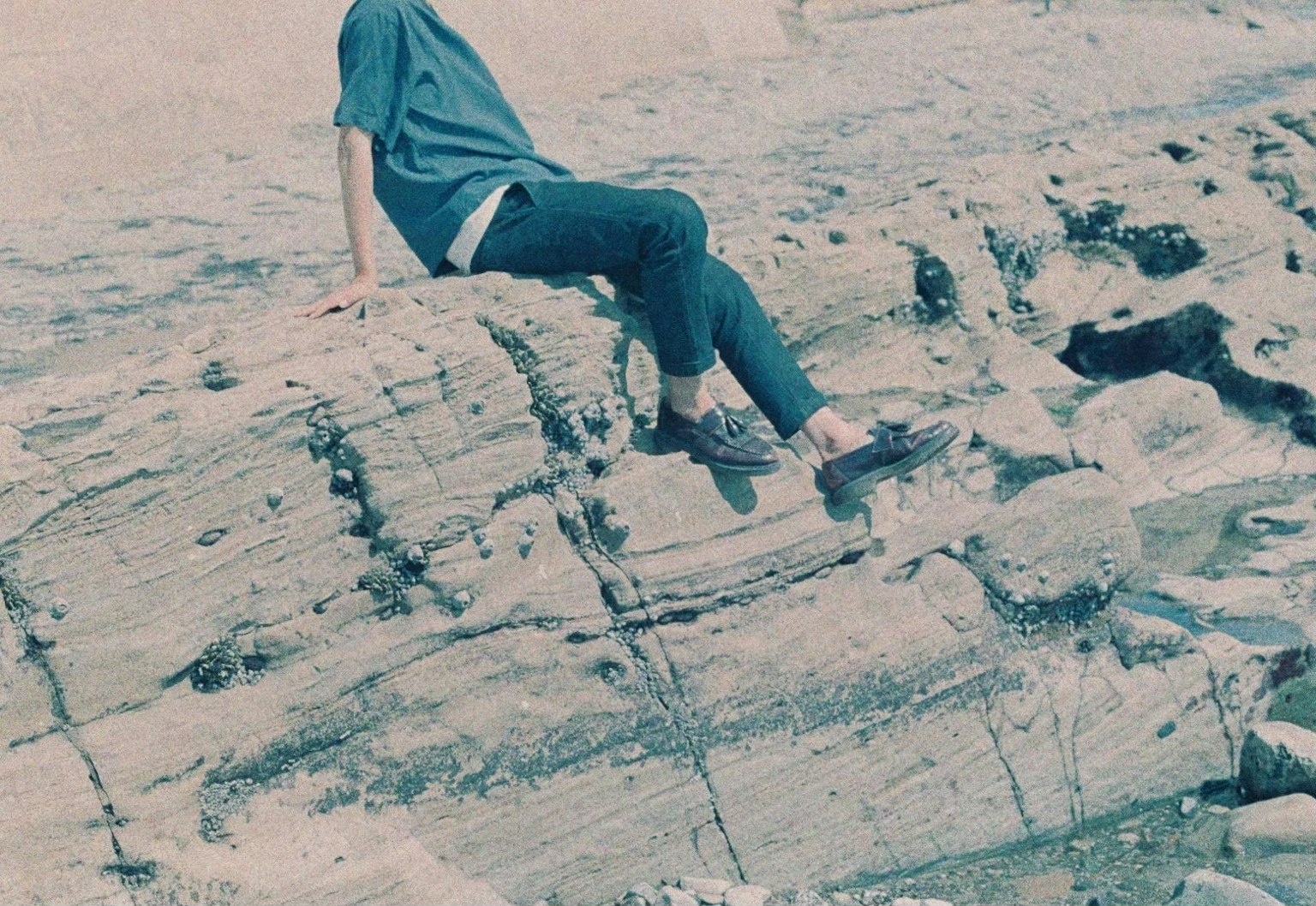 Orang duduk di atas batu mengenakan kemeja biru pemandangan alam