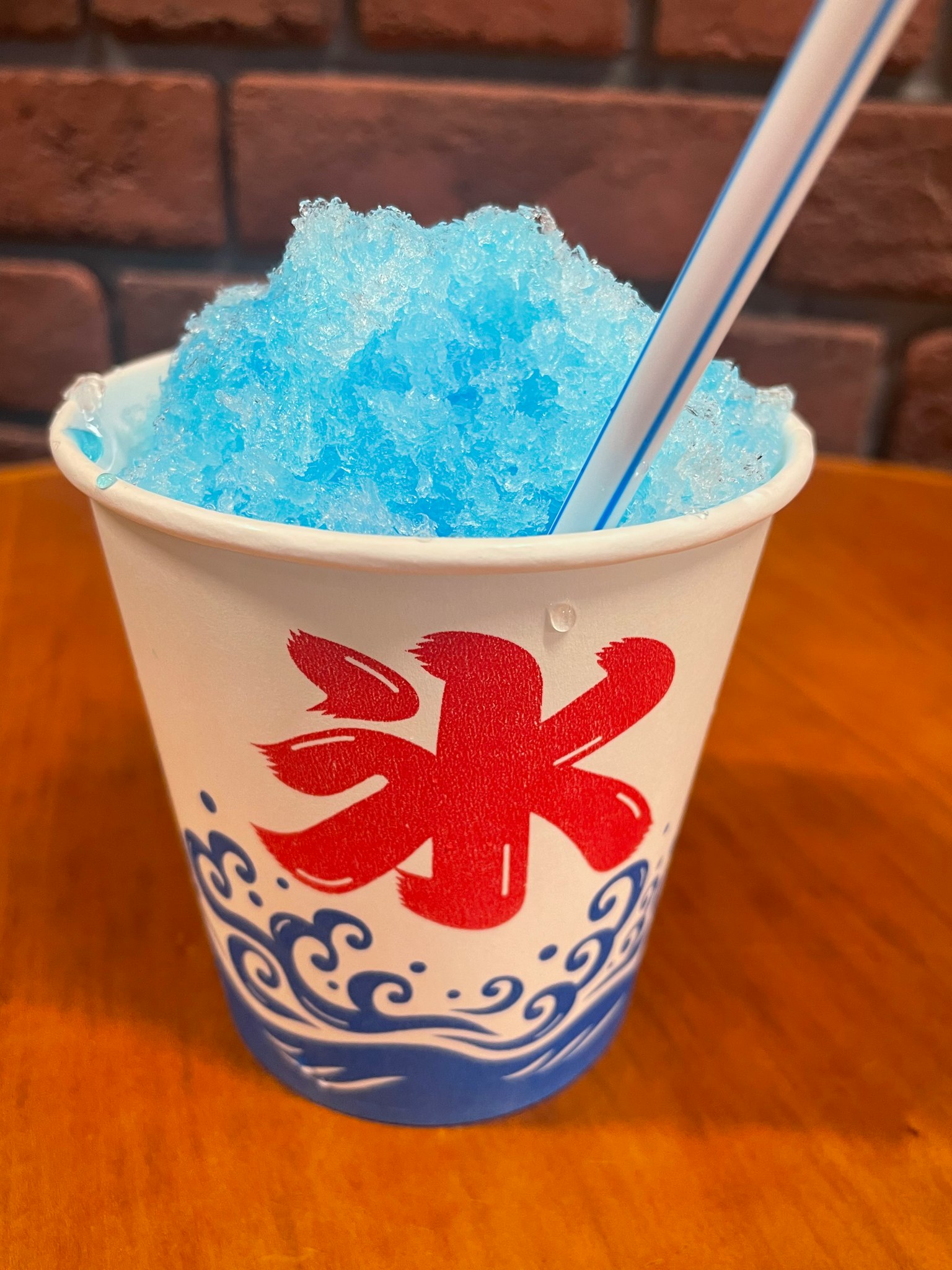 Una tazza di ghiaccio tritato blu con un carattere rosso e un design di onde
