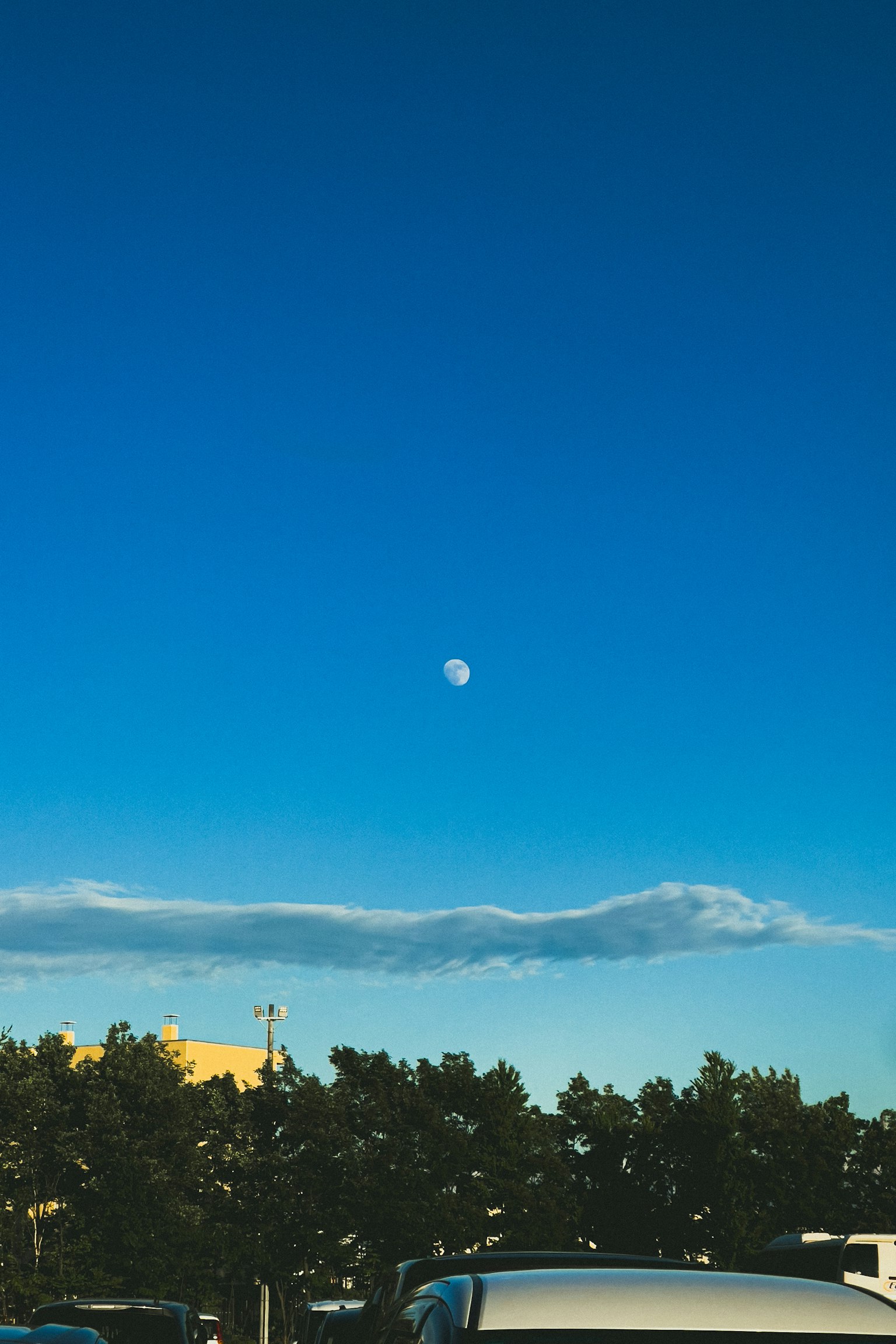 Luna en el cielo azul con nubes y árboles
