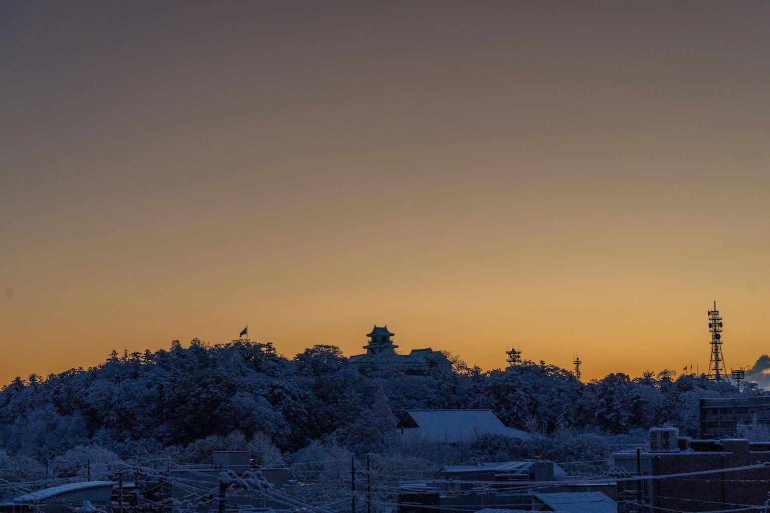 Schneebedeckte Hügel mit einem schönen orangefarbenen Sonnenuntergang im Hintergrund