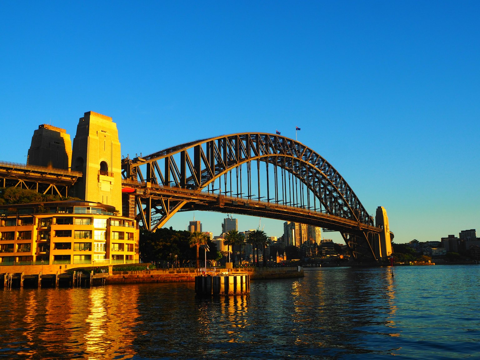 Pemandangan matahari terbenam yang indah dari Jembatan Pelabuhan Sydney dengan pantulan di air