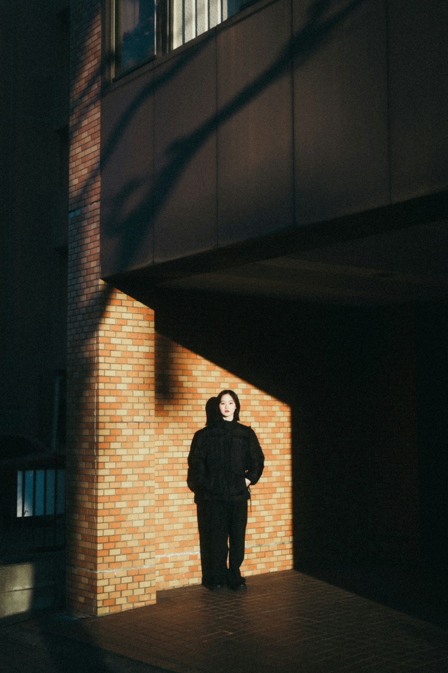 건물 앞에 서 있는 사람과 대조적인 그림자와 빛