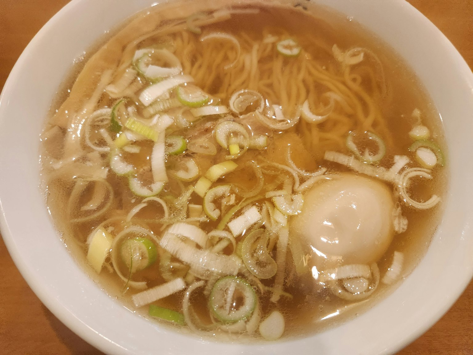 Schüssel mit Ramen und Brühe, garniert mit Frühlingszwiebeln und einem weichgekochten Ei