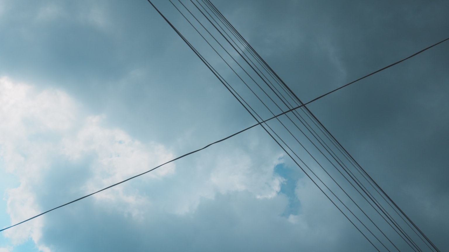 Foto di linee elettriche incrociate contro un cielo nuvoloso
