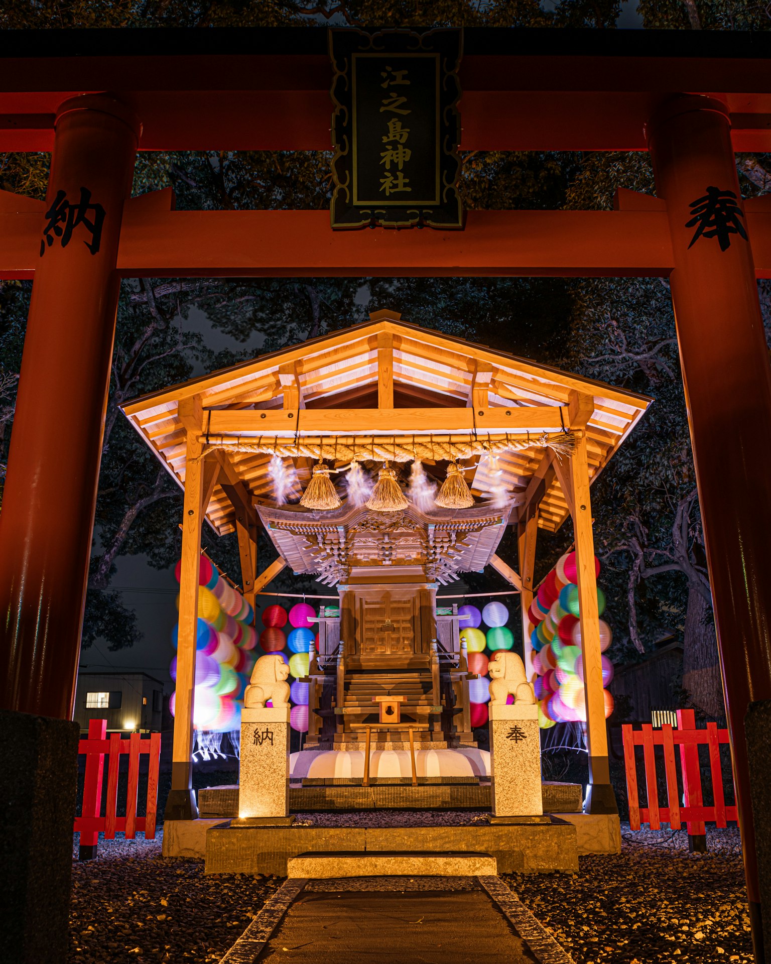 Torii illuminato di notte con un altare lanterne colorate decorano la scena