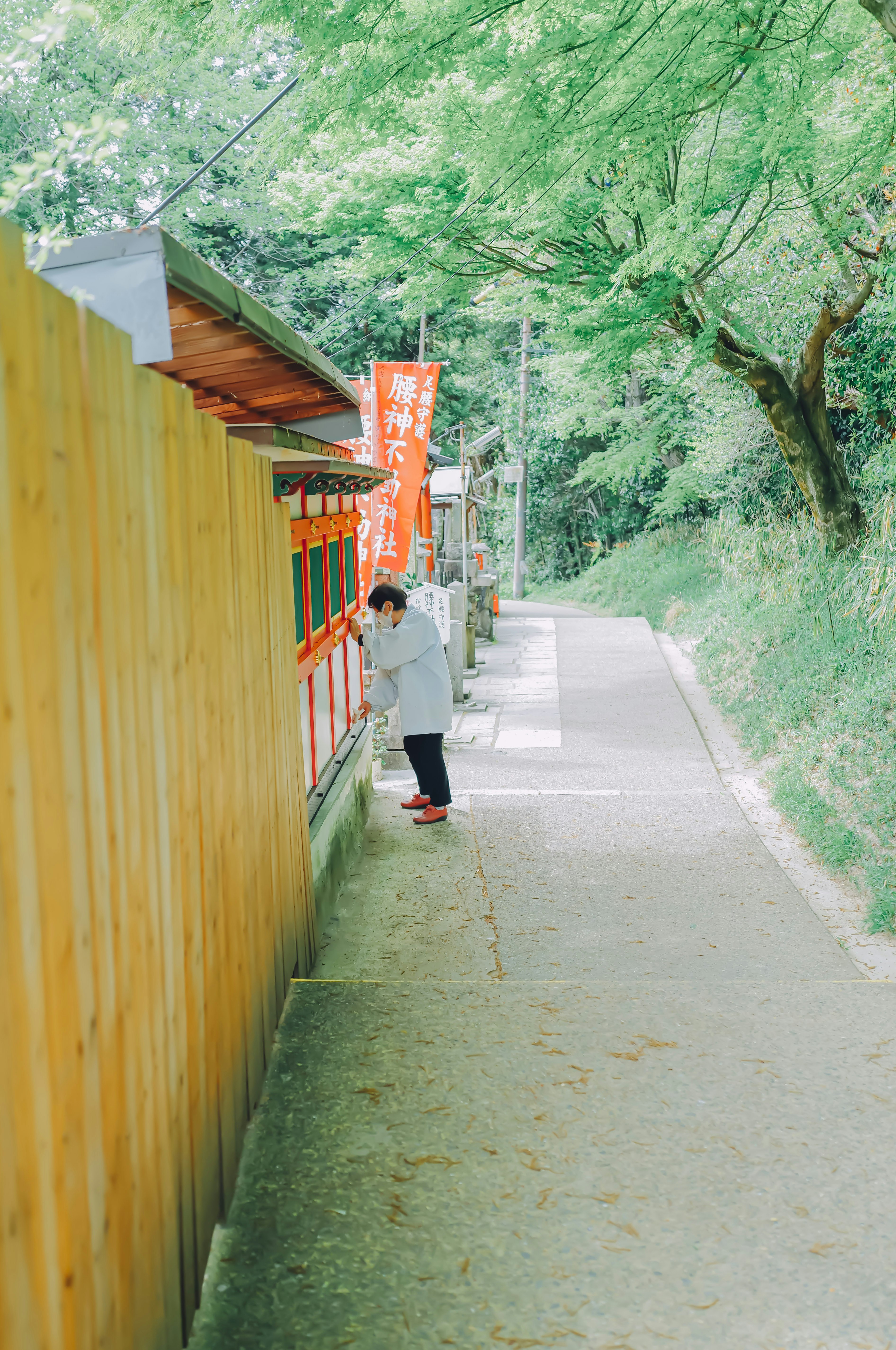 small storefront along a yellow wall on a green hillside path