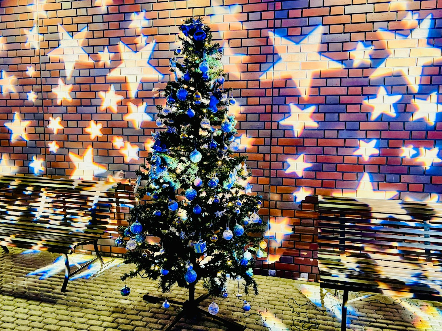 Árbol de Navidad con decoraciones azules y blancas frente a una pared estrellada