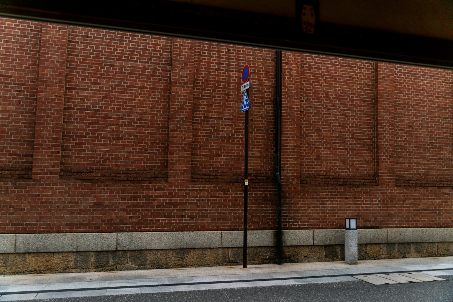 Scena urbana con muro di mattoni e segnale stradale viola
