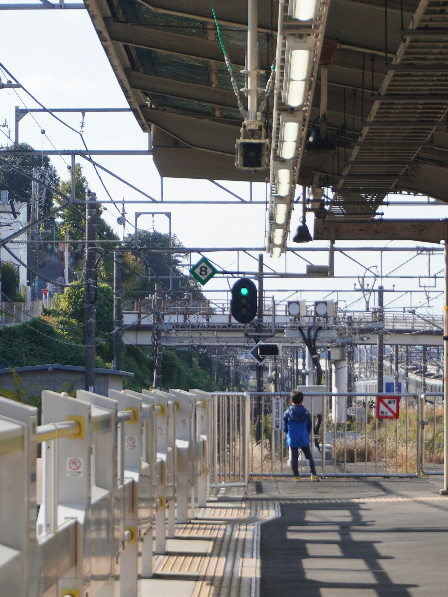 駅のプラットフォームに立つ人と信号機の緑色の光