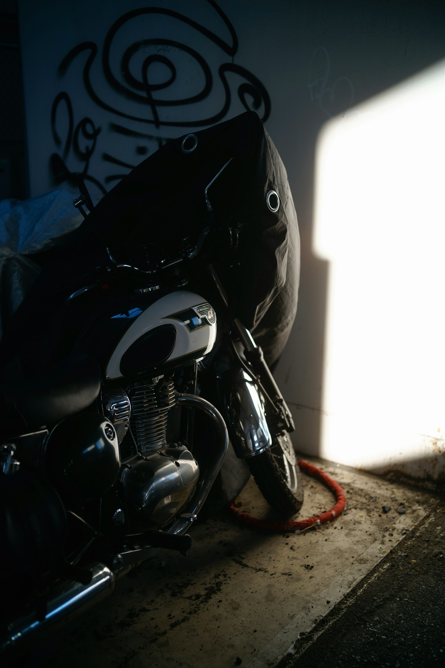 Ein schwarzes Motorrad, das an einer Wand lehnt, mit Schatten darauf