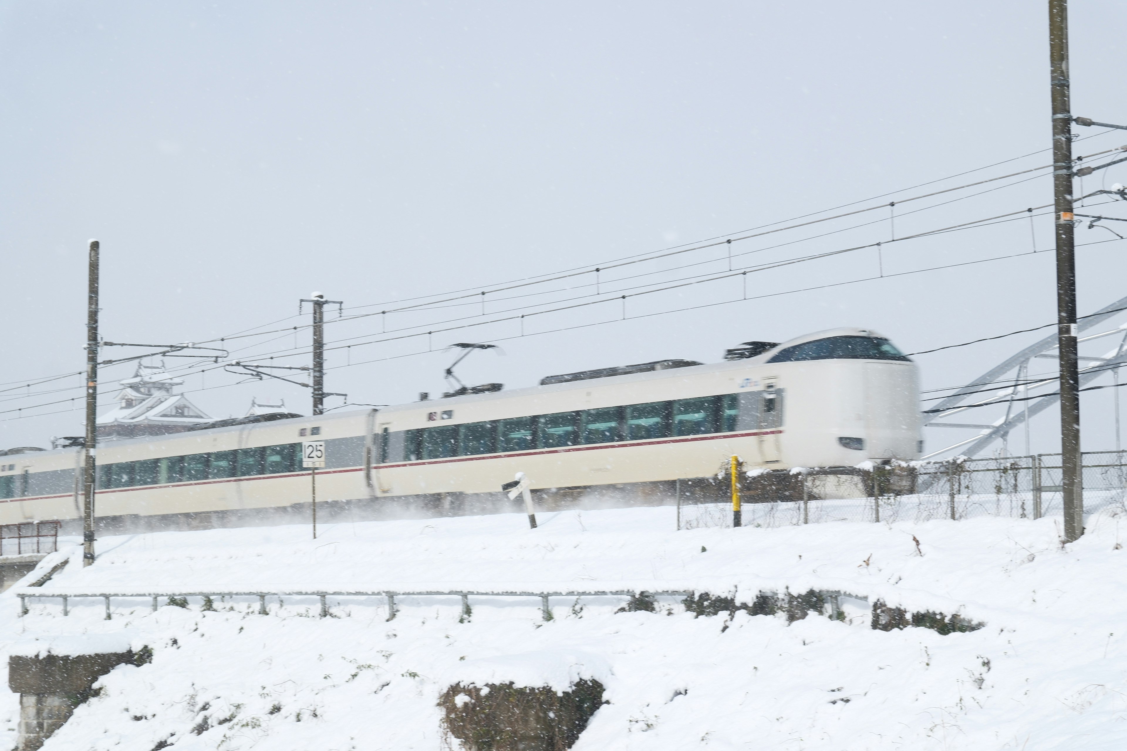 雪景色の福知山城近くを走る特急列車の車両