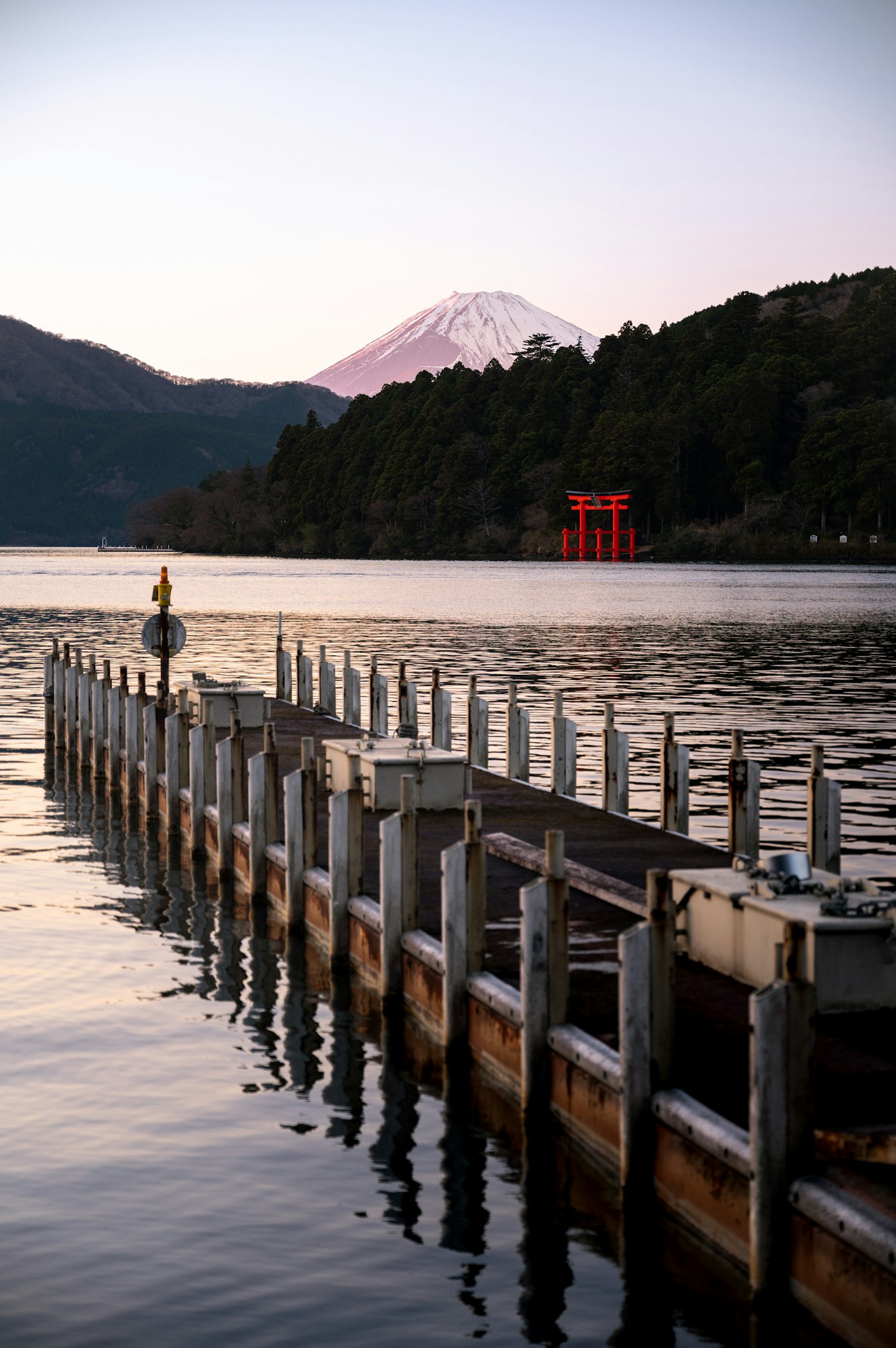 富士山が背景にある湖の桟橋の風景 赤い鳥居が見える