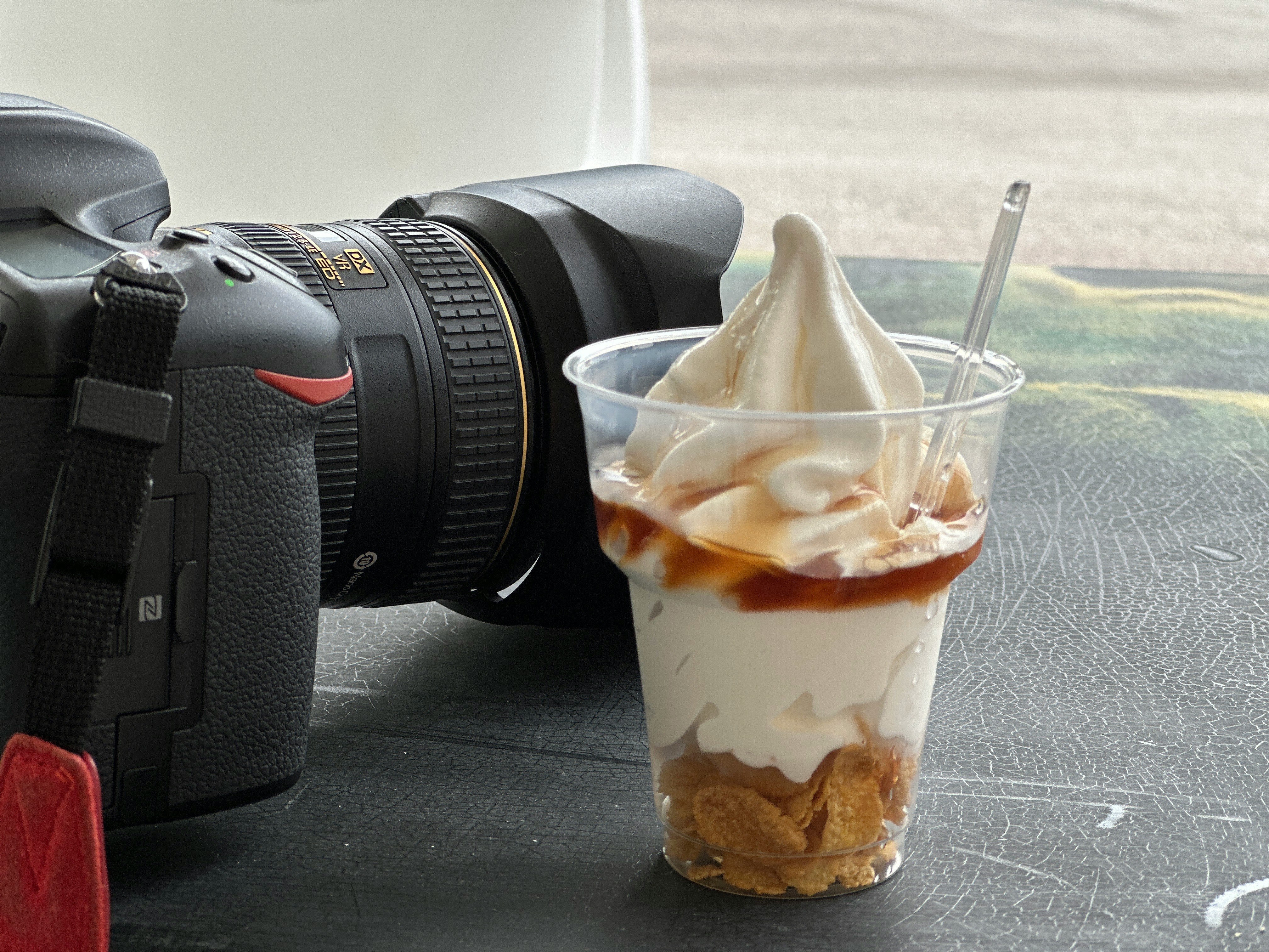 Nikonのカメラとスイーツのカップ