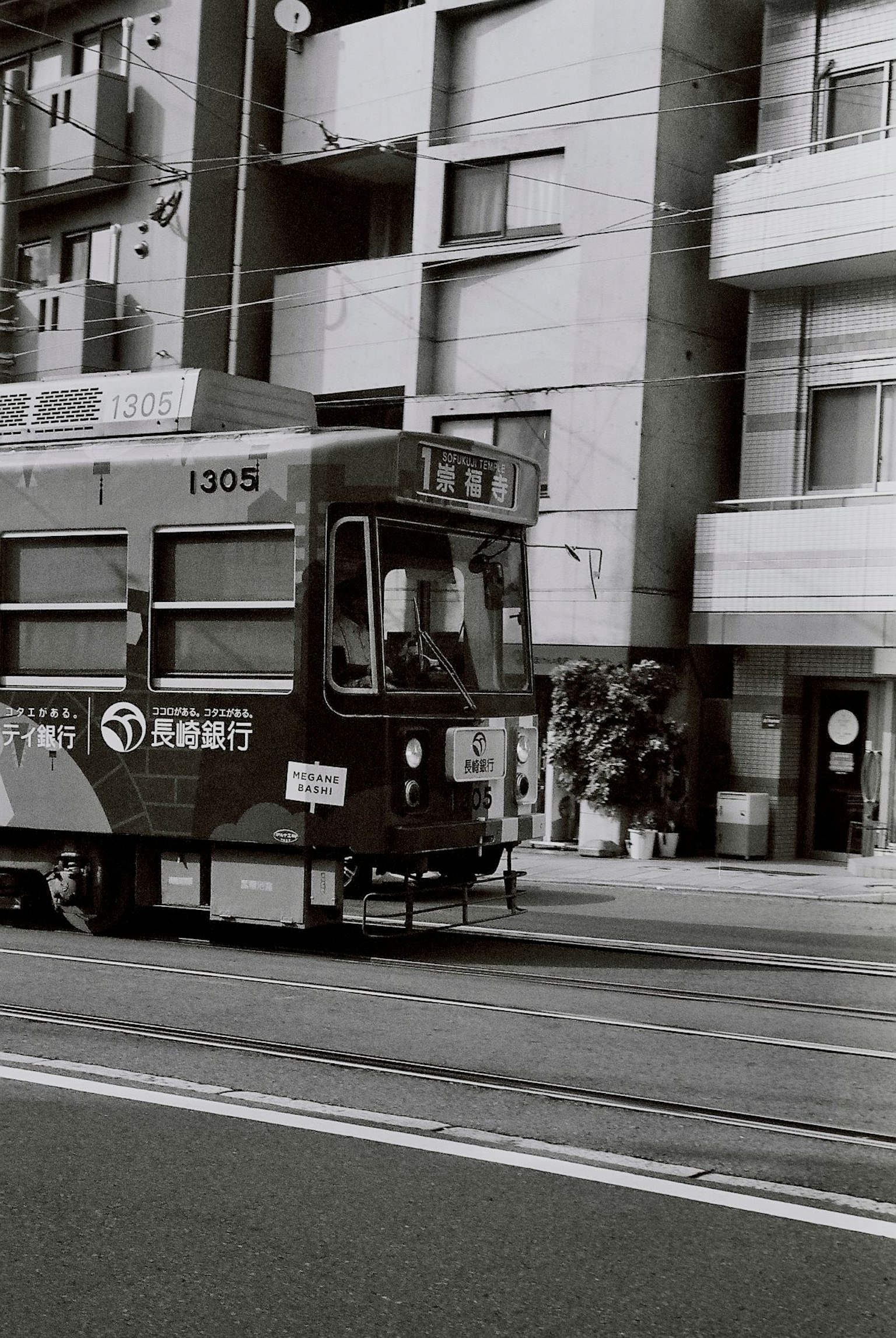 黑白電車在城市街道上行駛，周圍有建築物
