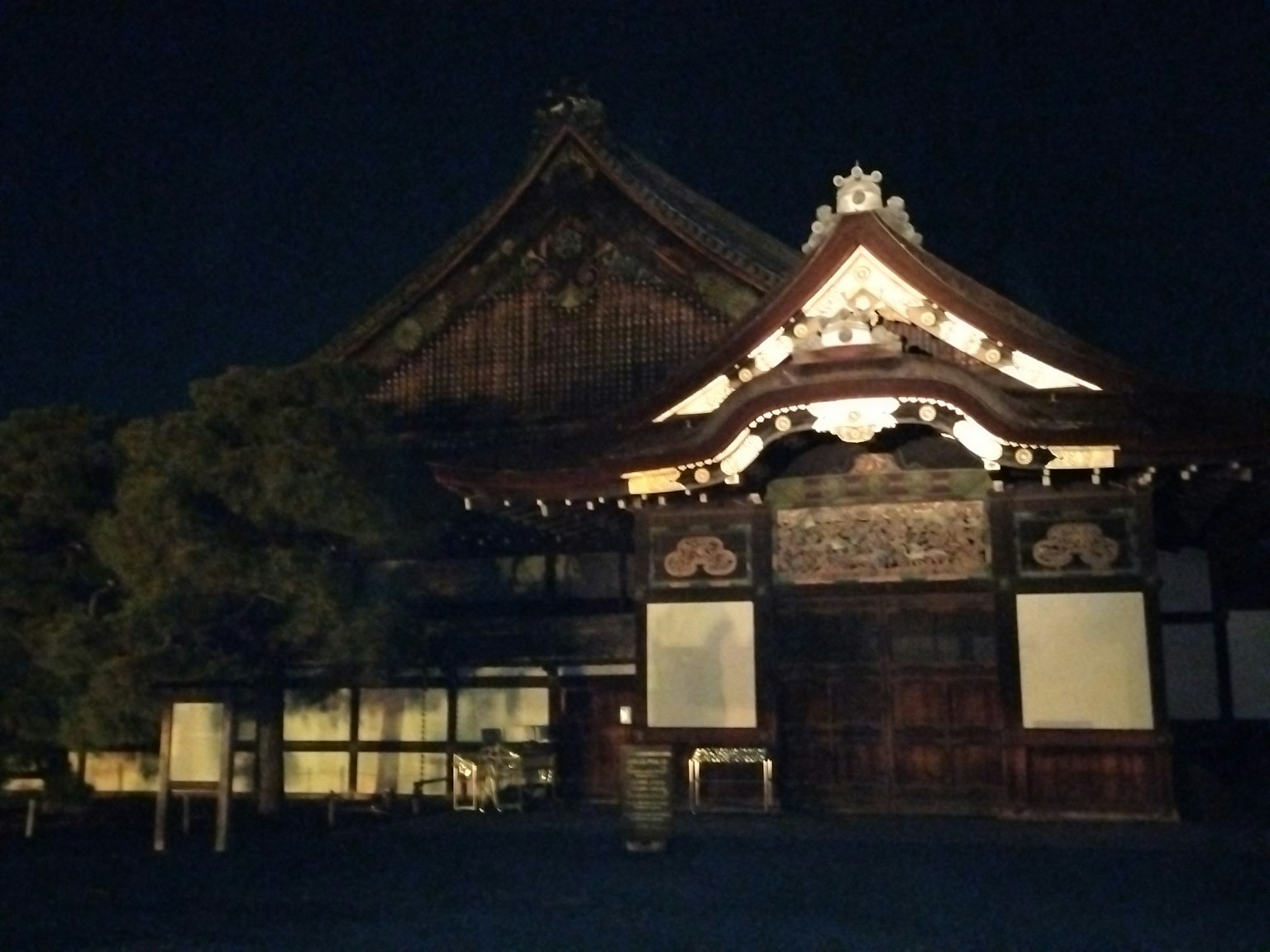 Außenansicht eines traditionellen japanischen Gebäudes bei Nacht mit Holzstruktur und verziertem Dach