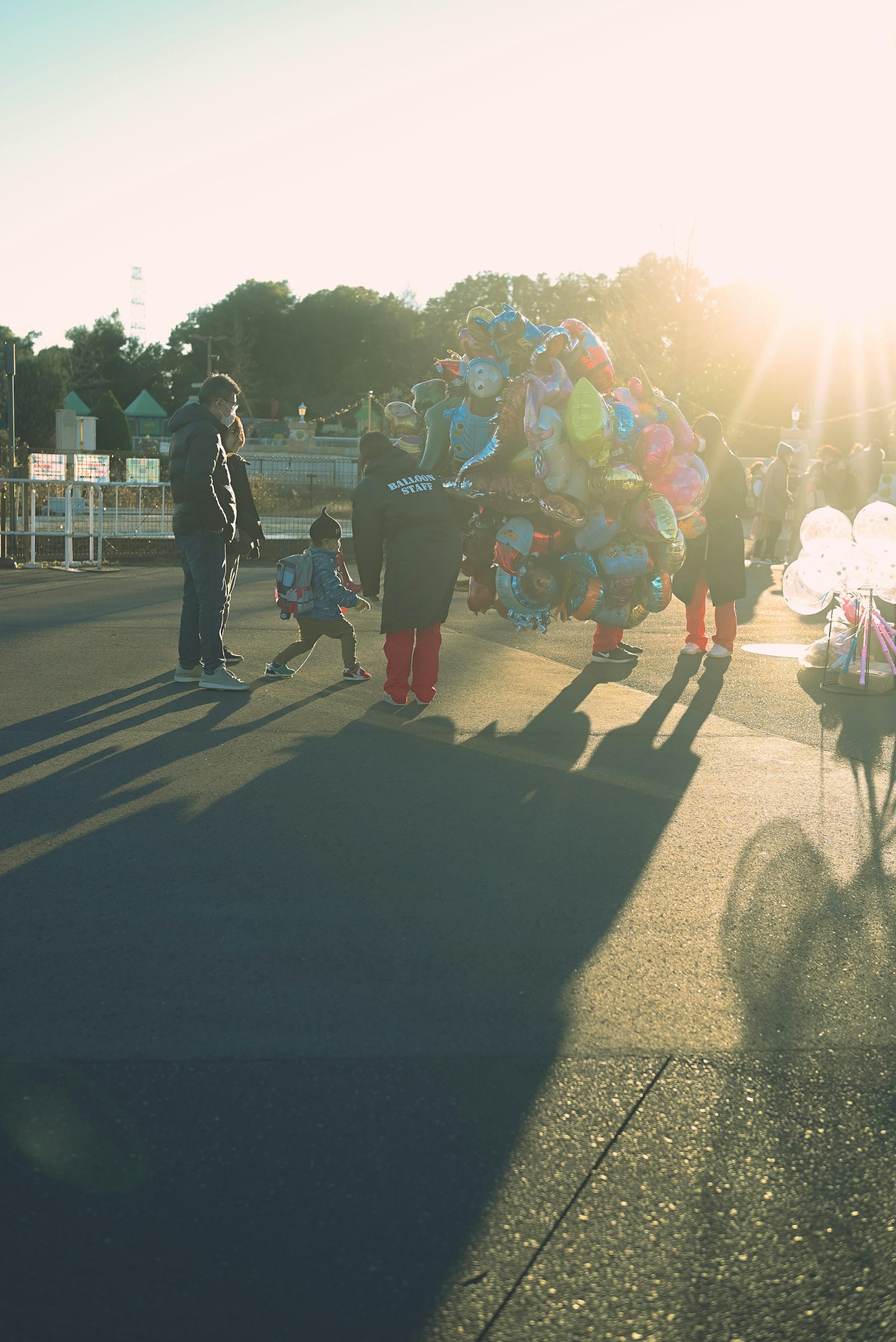 Personas caminando con globos coloridos contra un fondo de atardecer