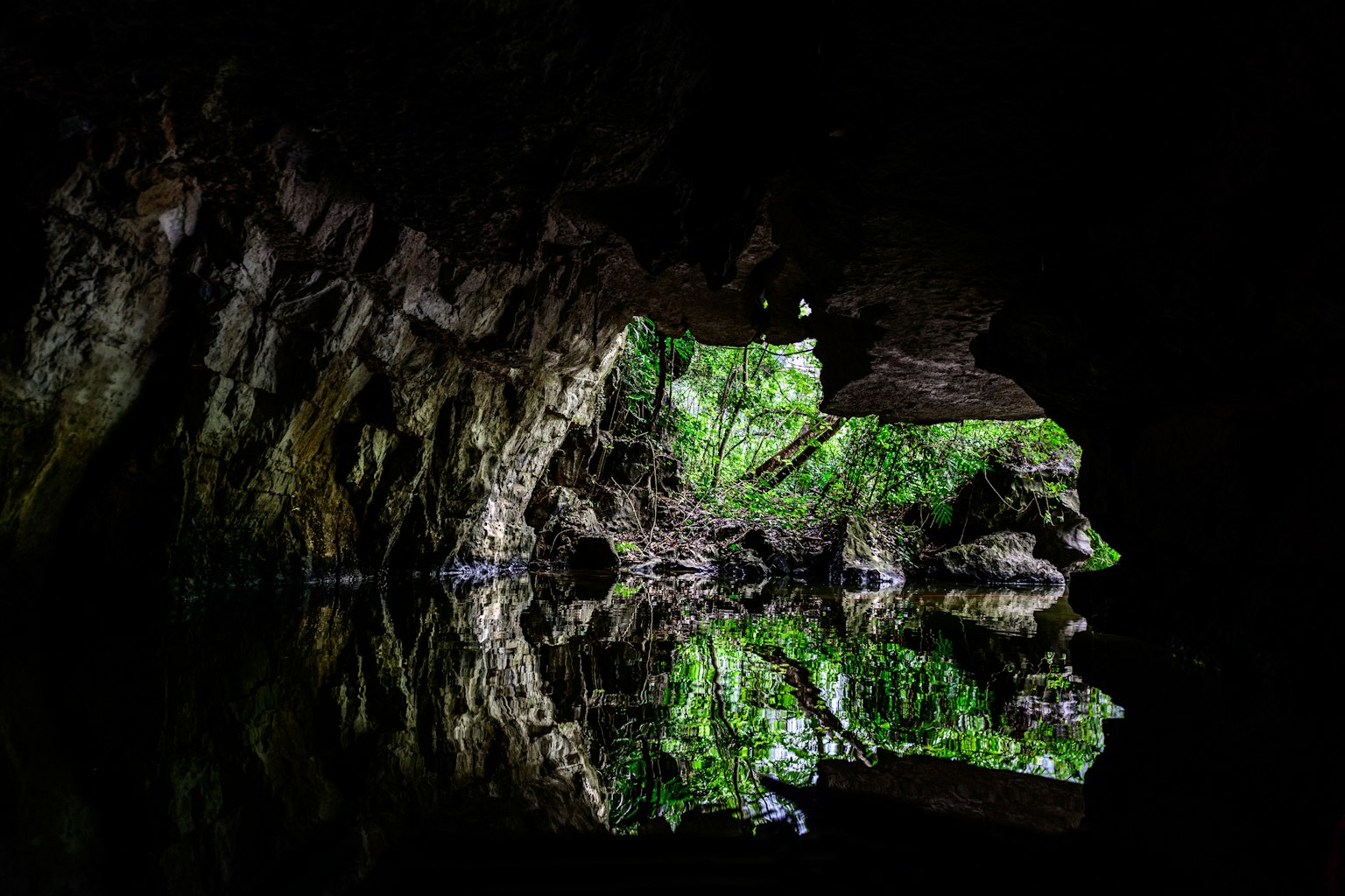 Dentro di una grotta con riflessi verdi e superficie d'acqua scura
